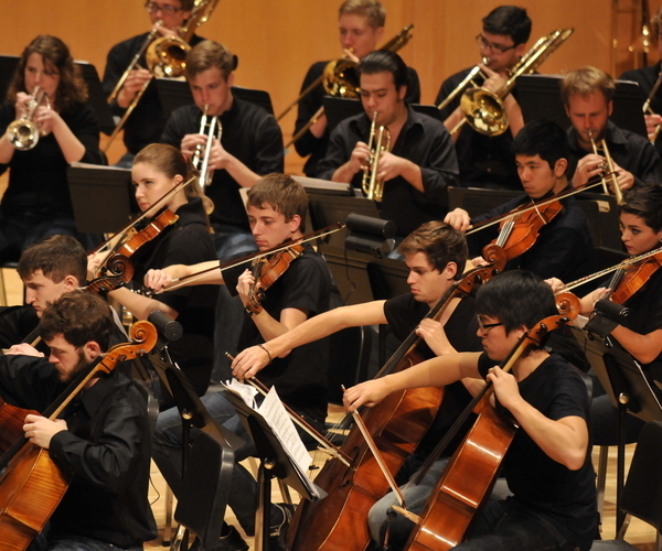 Symphony orchestra on stage, violins, cello and flute performing.